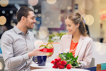 Image showing happy couple with present and flowers in mall