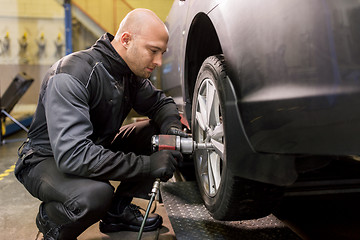 Image showing auto mechanic with screwdriver changing car tire