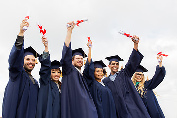 Image showing happy students in mortar boards with diplomas