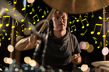 Image showing musician in headphones playing drum kit at concert