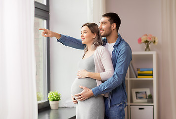 Image showing man showing something out window to pregnant wife