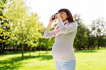 Image showing happy pregnant asian woman with camera at park