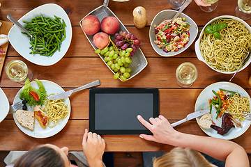 Image showing women with tablet pc at table full of food