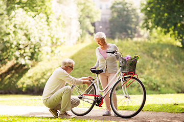 Image showing happy senior couple with bicycle at summer park