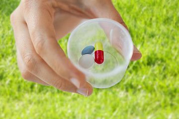 Image showing close up of female hand with pills in medicine cup