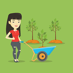 Image showing Woman pushing wheelbarrow with plant.