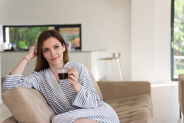 Image showing young woman in a bathrobe enjoying morning coffee