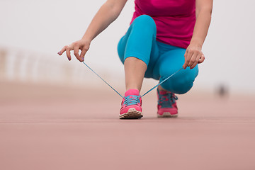 Image showing Young woman tying shoelaces on sneakers