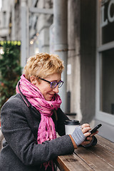 Image showing Woman browsing smartphone in outside cafe