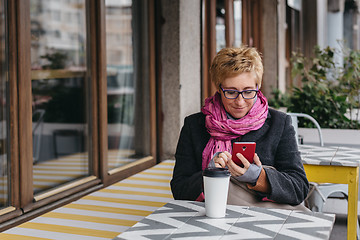 Image showing Adult woman with coffee and smartphone