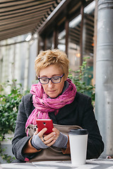 Image showing Smiling woman with phone in cafe