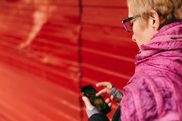 Image showing Woman texting at red wall