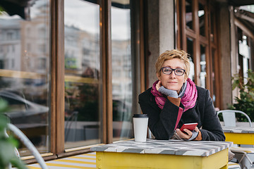 Image showing Dreamy woman with phone in cafe