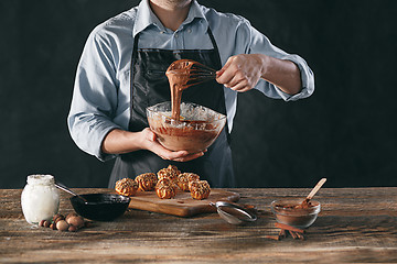 Image showing Decorating delicious homemade eclairs with chocolate and peanuts