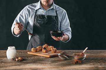 Image showing Decorating delicious homemade eclairs with chocolate and peanuts