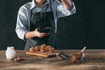 Image showing Decorating delicious homemade eclairs with chocolate and peanuts