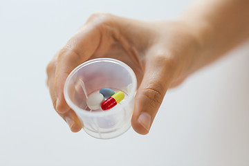 Image showing close up of female hand with pills in medicine cup