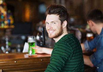 Image showing happy man drinking green beer at bar or pub