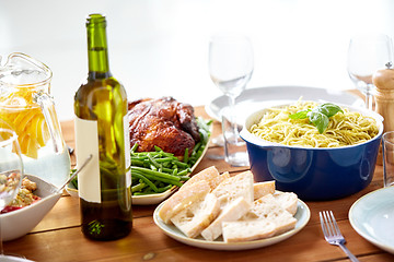 Image showing bottle of wine and food on served wooden table