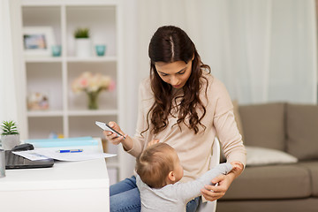 Image showing baby boy disturbing mother working at home