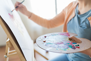 Image showing artist with palette and brush painting at studio