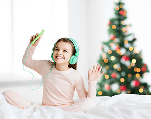 Image showing girl with smartphone and headphones at christmas