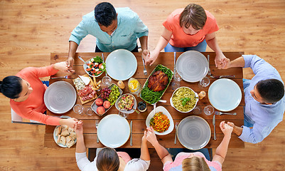 Image showing group of people at table praying before meal