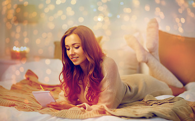 Image showing happy young woman with notebook in bed at home