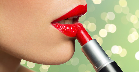 Image showing close up of woman applying red lipstick to lips