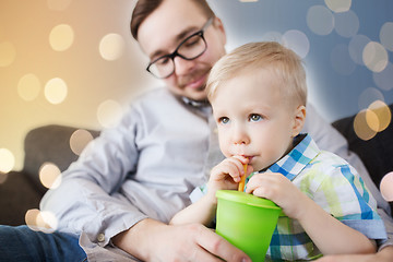 Image showing father and son drinking from cup at home