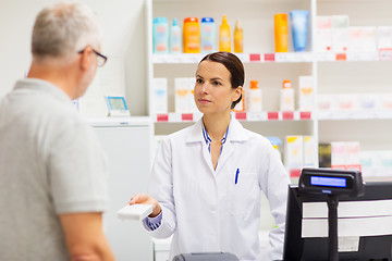 Image showing apothecary showing drug to senior man at pharmacy