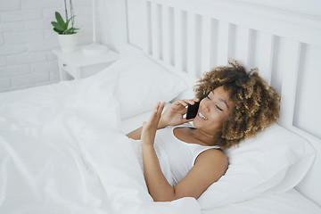 Image showing Content woman talking on phone in bed