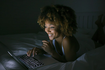 Image showing Smiling woman chatting with laptop in dark