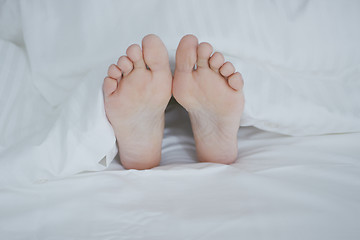 Image showing Crop female feet under blanket