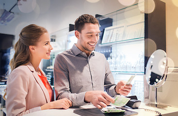 Image showing happy couple paying for purchase in store