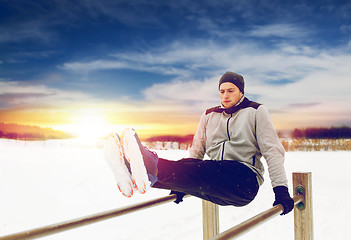 Image showing young man exercising on parallel bars in winter