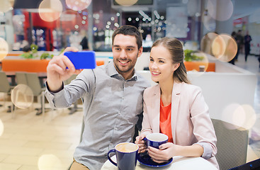 Image showing happy couple with smartphone taking selfie in mall