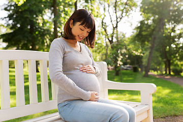 Image showing happy pregnant asian woman sitting on park bench