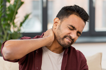 Image showing unhappy man suffering from neck pain at home