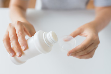 Image showing woman pouring syrup from bottle to medicine cup