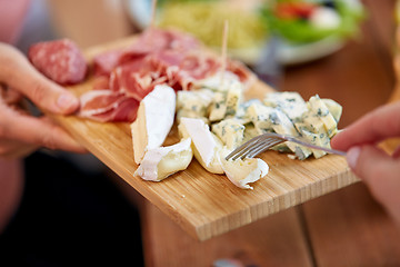 Image showing hands with blue cheese and jamon or ham on board