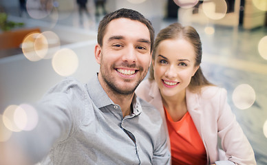 Image showing happy couple taking selfie in mall or office