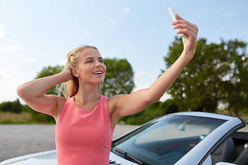 Image showing woman posing at convertible car and taking selfie