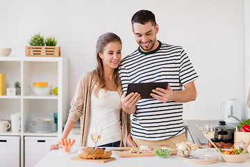 Image showing happy couple with tablet pc cooking food at home