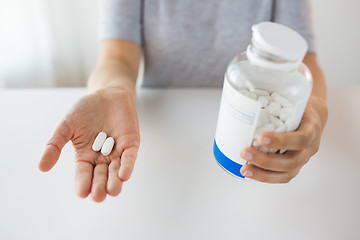 Image showing close up of hands holding medicine pills and jar