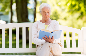 Image showing senior woman reading book at summer park