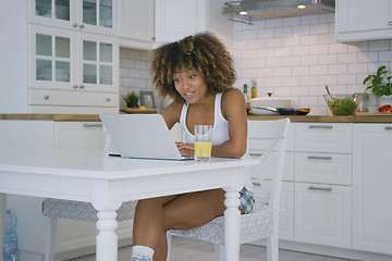 Image showing Young woman using laptop in kitchen