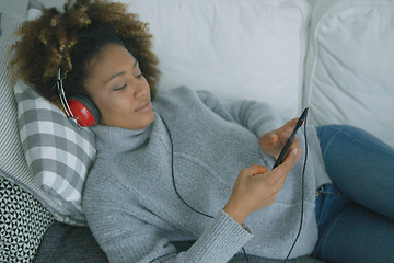 Image showing Young woman chilling on sofa with gadgets