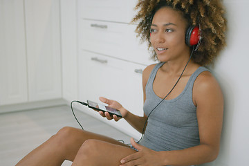 Image showing Young woman with headphones in kitchen