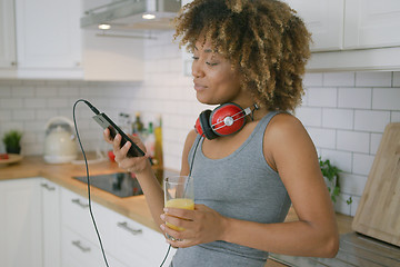 Image showing Casual woman relaxing with phone in kitchen